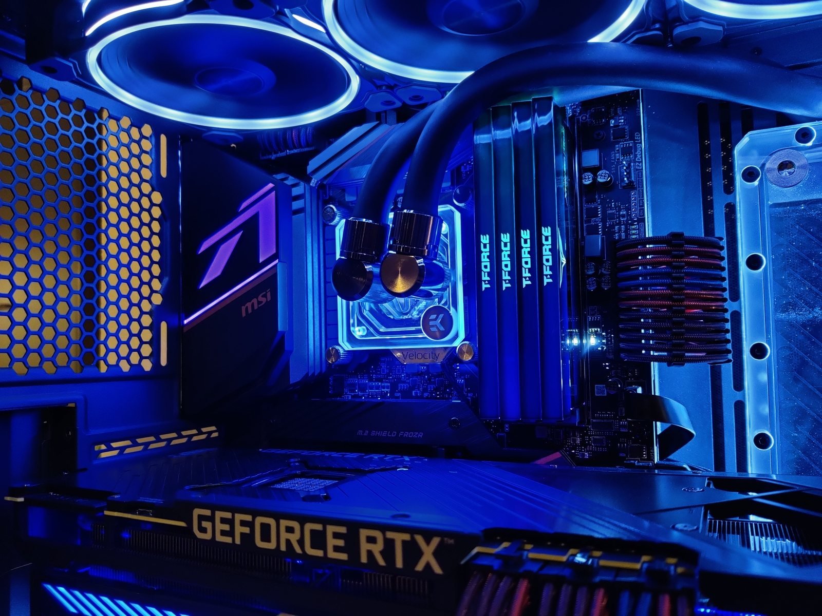 Innenraum eines wassergekühlten PCs mit sauber geführten Kabeln und beleuchteter Hardware